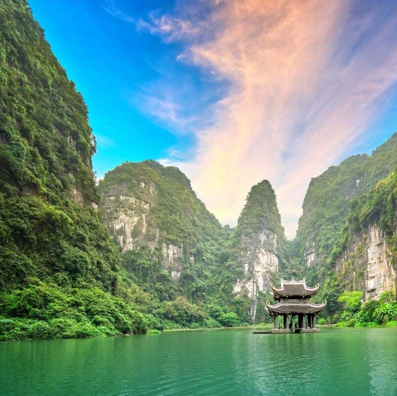 green blue water with green mountains on eaither side and a temple in the middle