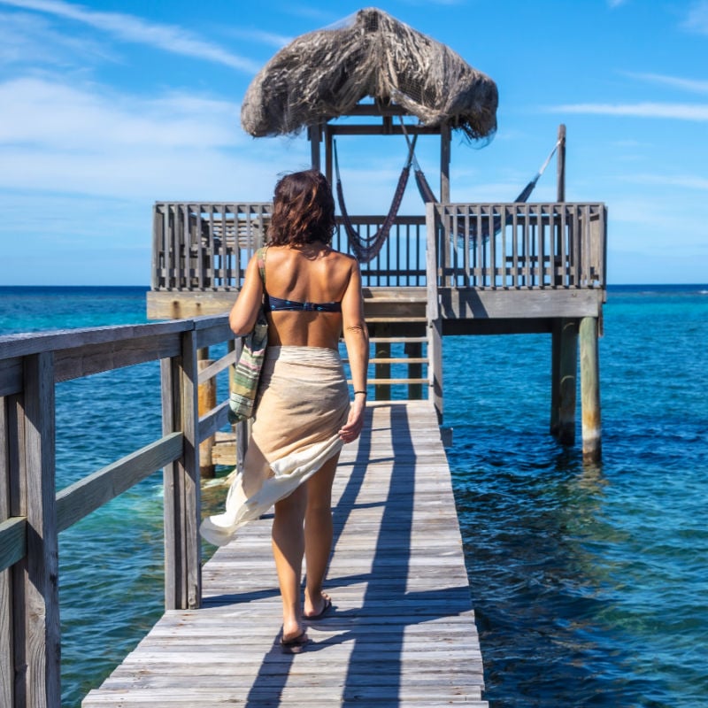 A young girl at a wooden construction of the Caribbean Sea on Roatan Island. Honduras copy