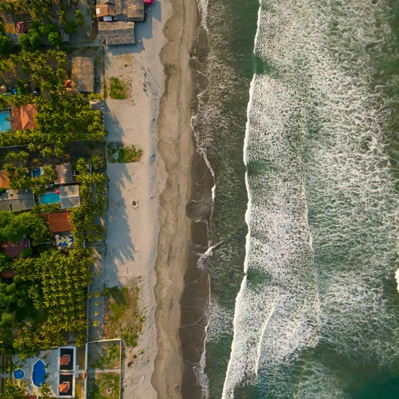 An aerial view directly above the shoreline of the Costa del Sol beach in La Paz, El Salvador