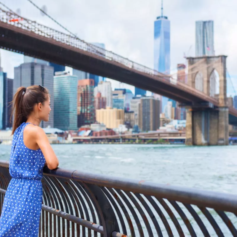 New York City woman looking at Brooklyn Bridge and view of downtown Manhattan skyline