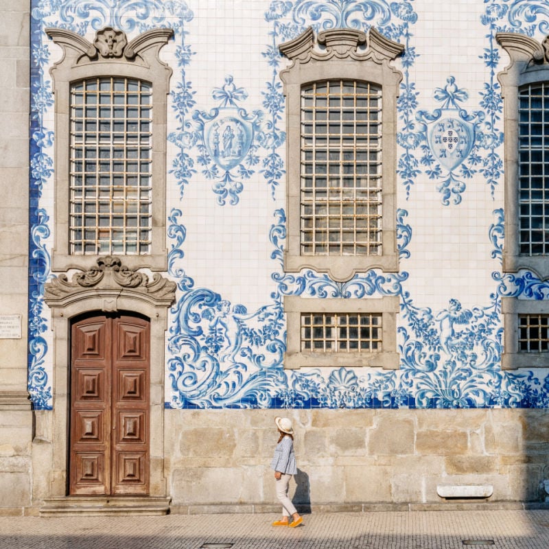 Tourist walking, azulejos tiles over Chapel Of Souls, Porto, Portugal