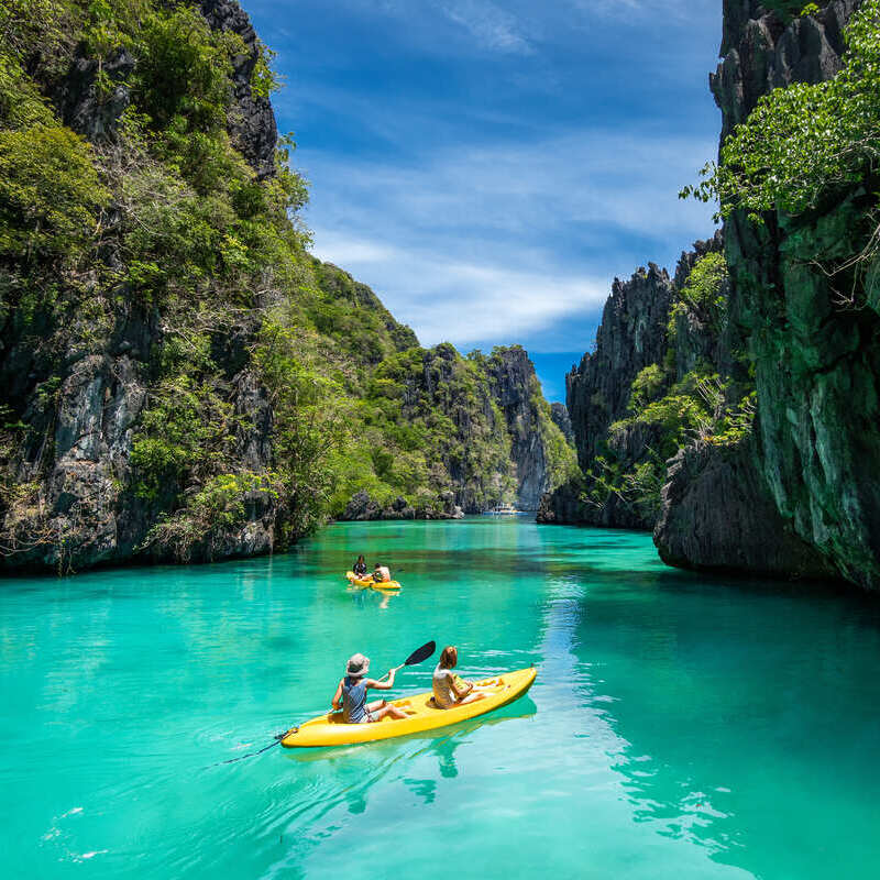 Tourists Kayaking Through Karst Cliffs In Palawan, The Philippines, Southeast Asia