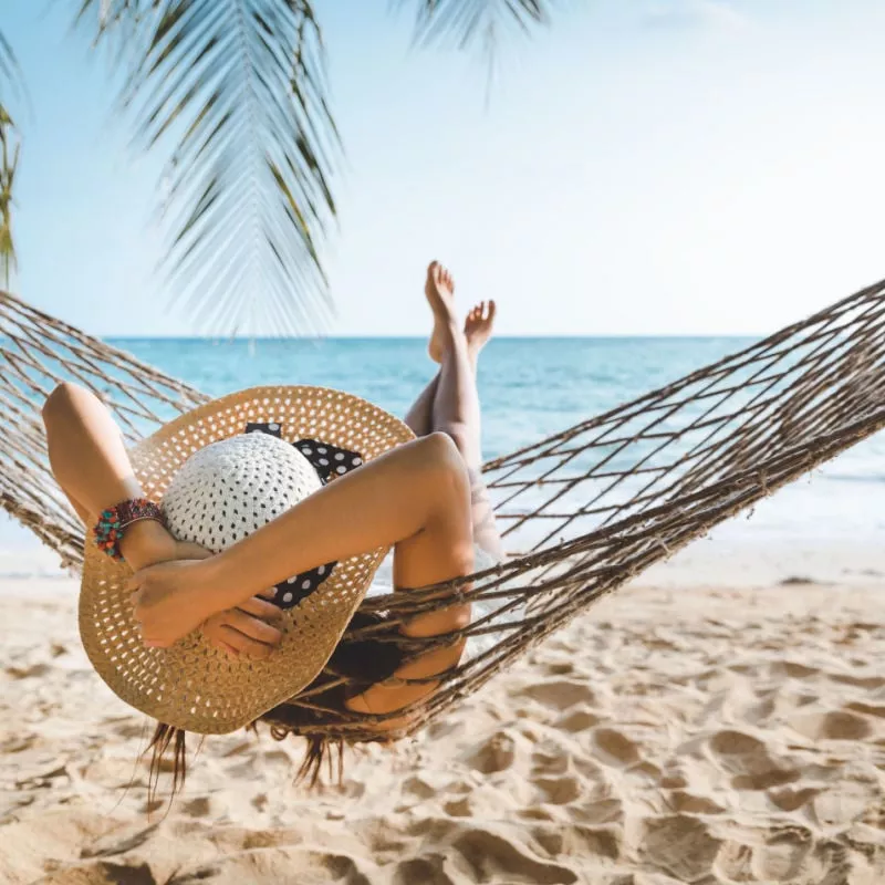 Travel vacation concept, Happy traveler n with white bikini relaxing in hammock on beach