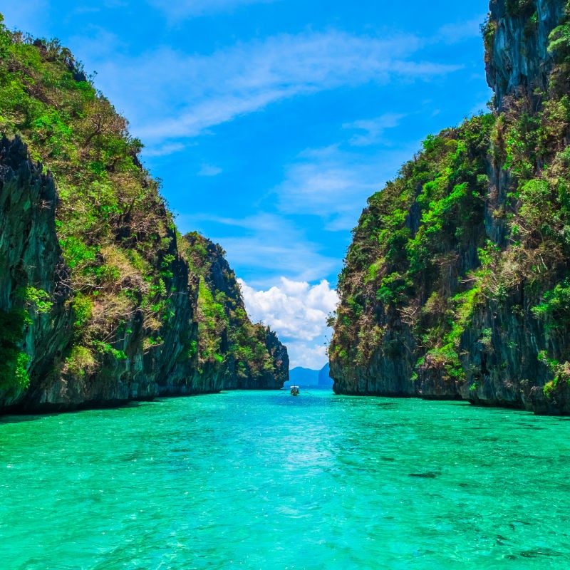 Tropical Landscape With Rock Islands, A Lonely Boat, And Crystal Clear Water In Palawan, Philippines, Southeast Asia