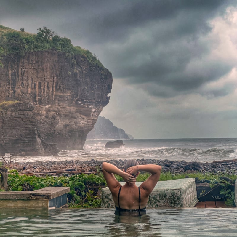 Woman in pool looking at cliff in El Salvador