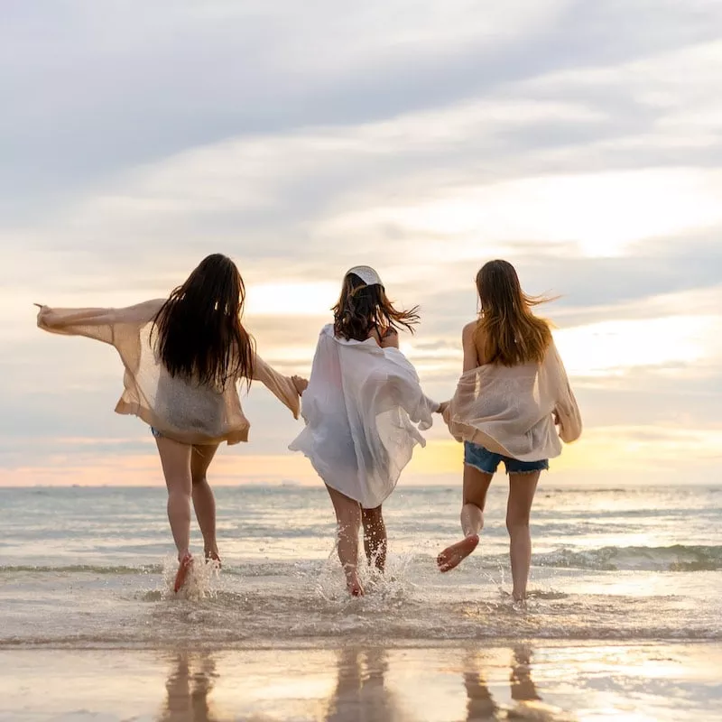 Three Women Having Fun At The Beach During Sunset