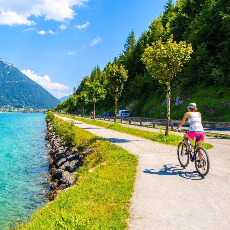 woman biking alongside a water body in Austria