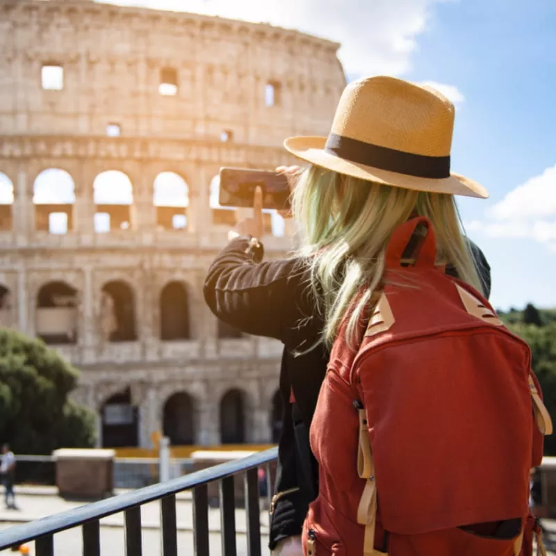 Back view of young woman with hat she's take a picture by smartphone at Colosseum in Rome, Italy. Rome architecture and landmark copy