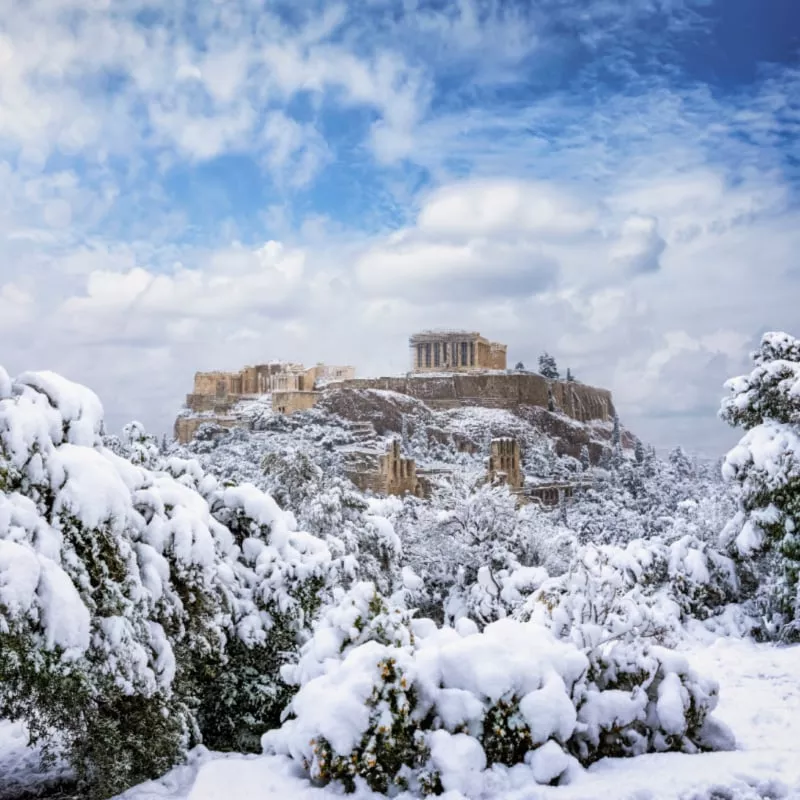 Beautiful view to the Parthenon Temple at the Acropolis of Athens, Greece, with thick snow and blue sky during winter