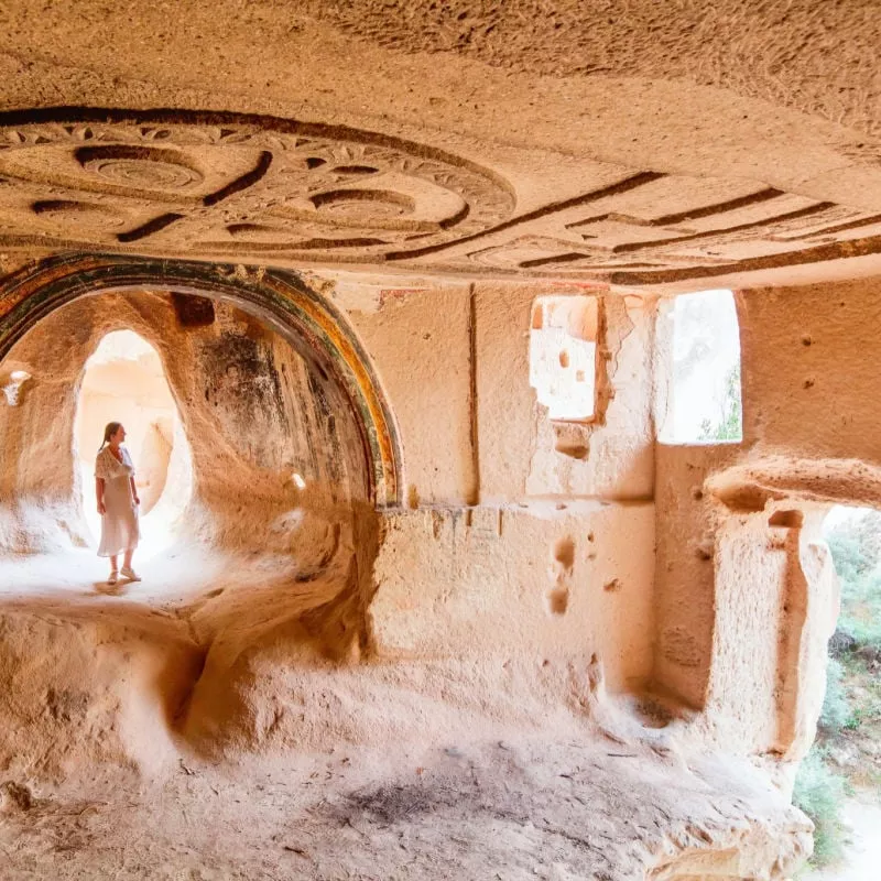 woman touring cave church of Three Crosses in Rose Valley in Cappadocia Turkey