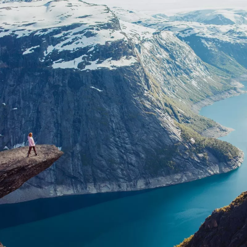 young red girl sneakers stands on a rock and watching the sunset and the mountains, overnight in tent a trip to the mountains, the language of the Troll, Norway fjords, cold weather copy