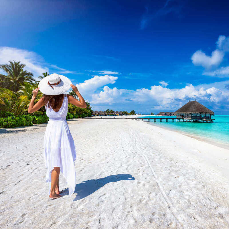 A Young Woman Wearing A White Dress As She Walks On A Tropical Beach In An Unspecified Tropical Location, Probably The Caribbean