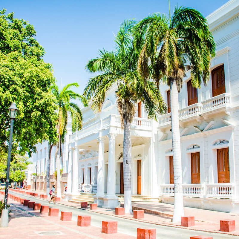 Colonial Style Whitewashed Building Flanked By Palm Trees In Santa Marta, Northern Coast Of Colombia, South America