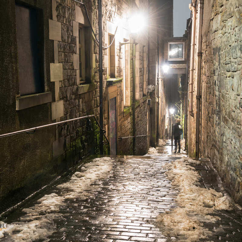 Male Tourist Walking Down A Narrow Alley Or Close In Old Town Edinburgh, Scotland, United Kingdom, North Western Europe