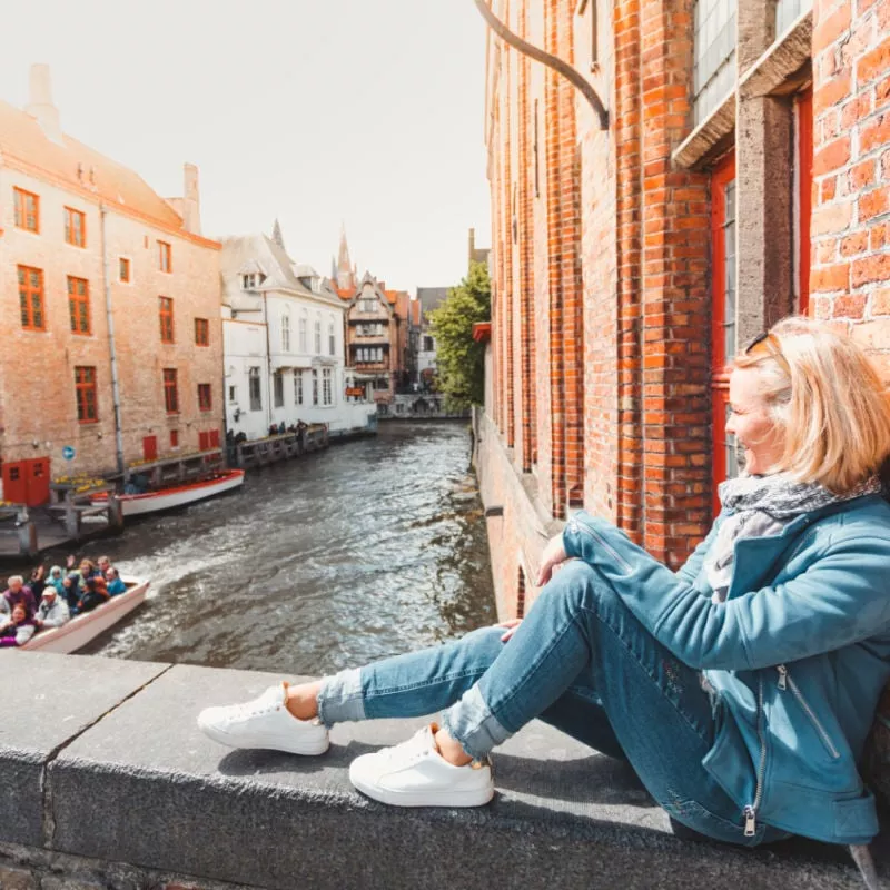 woman sitting on a bridge near the river in Bruges, Belgium