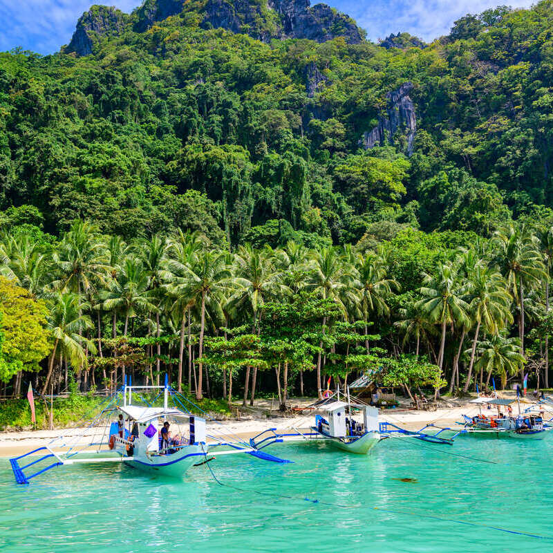 Boats Docked By A White Sand Beach In A Tropical Island, Mauritius, East Africa