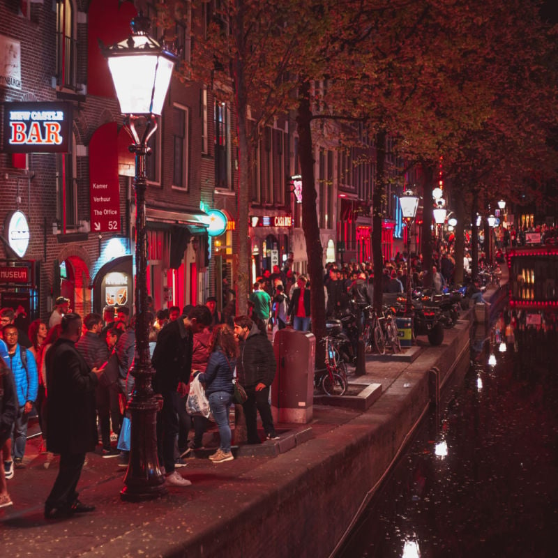 Crowd of international tourists walking on streets of Red Light District of Amsterdam.