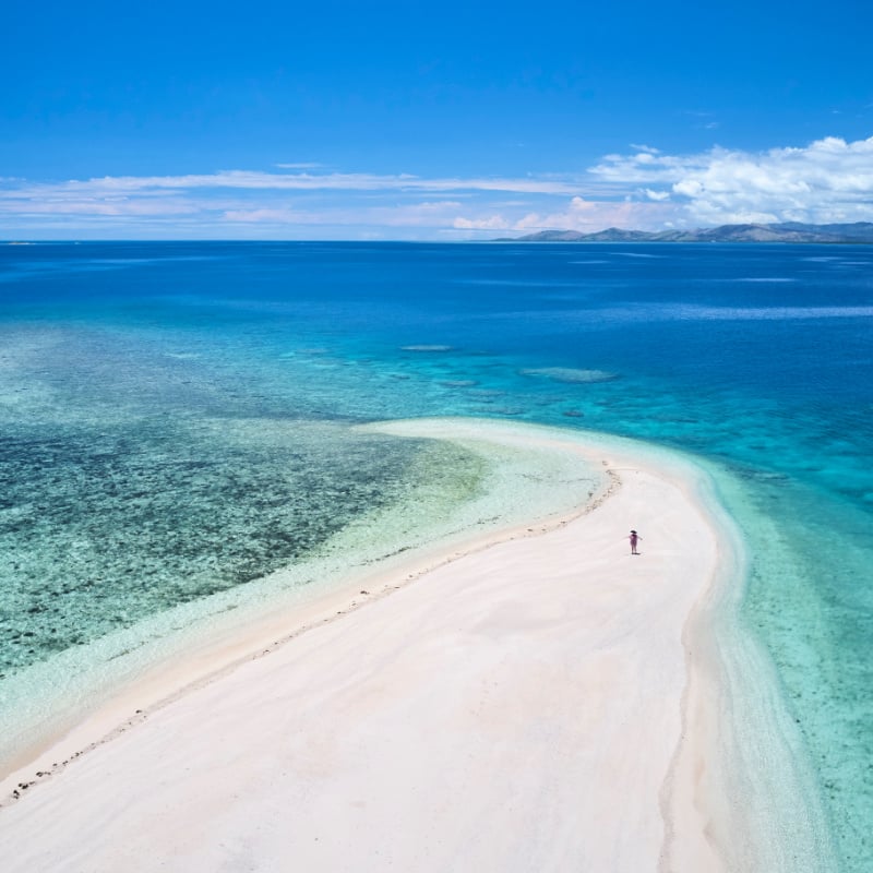 woman walking on beautiful white sands on remote island in fiji