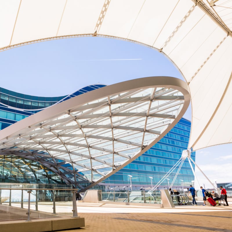 passengers entering denver international airport under large sun shade canopy