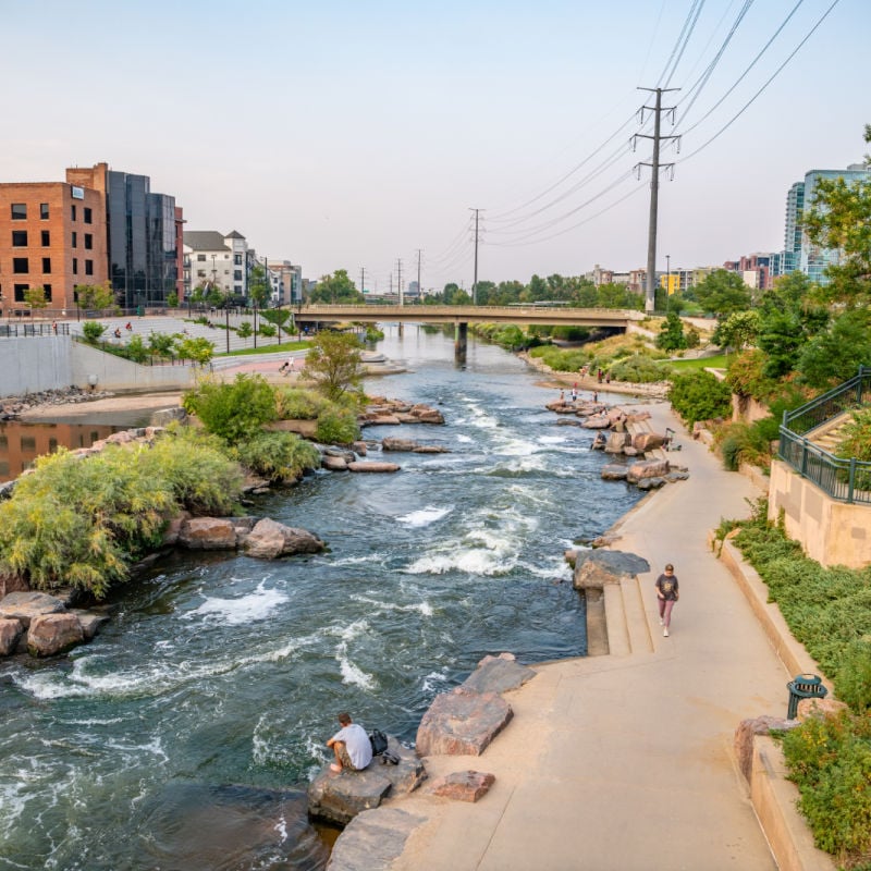 woman walking alongside a river in confluence park in denver colorado