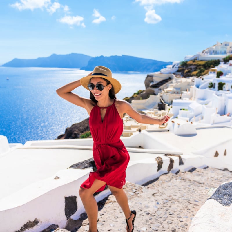 Travel Tourist Happy Woman Running Stairs Santorini, Greek Islands, Greece, Europe. Girl on summer vacation visiting famous tourist destination having fun smiling in Oia