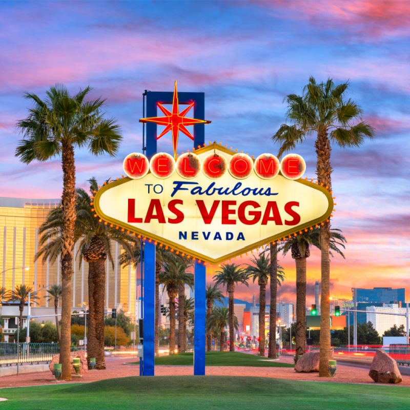 The famous Las Vegas sign with palm trees at sunset