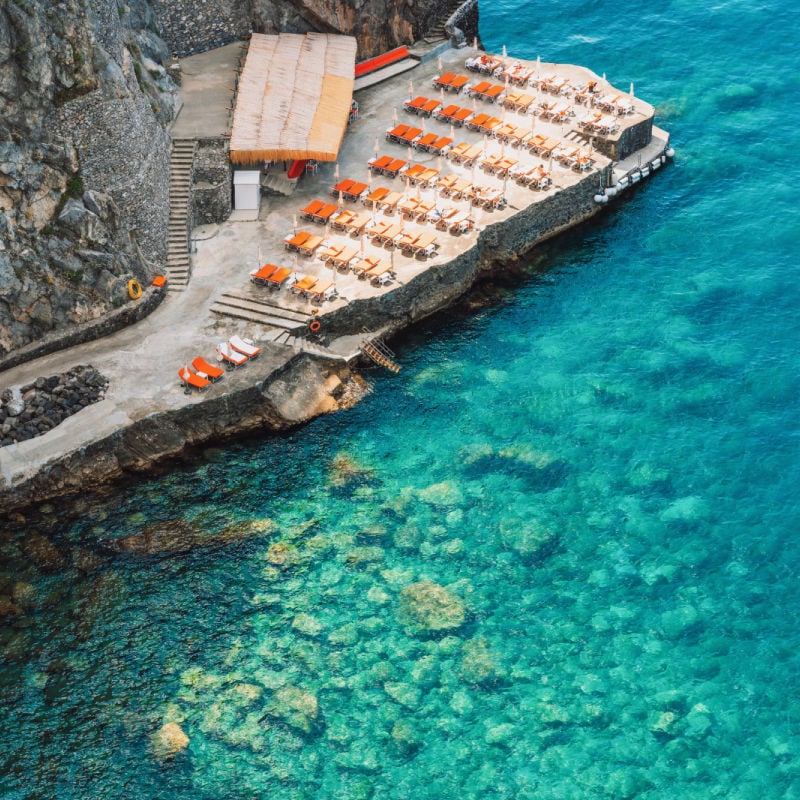 sunbeds and beautiful turquiose water at positano beach in amalfi italy