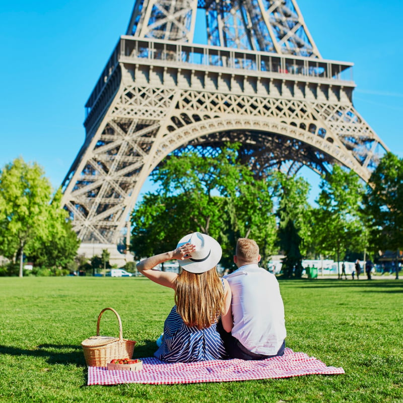 A Young Couple Having A Romantic Picnic At Champs de Mars, At The Foot Of The Eiffel Tower, Paris, France