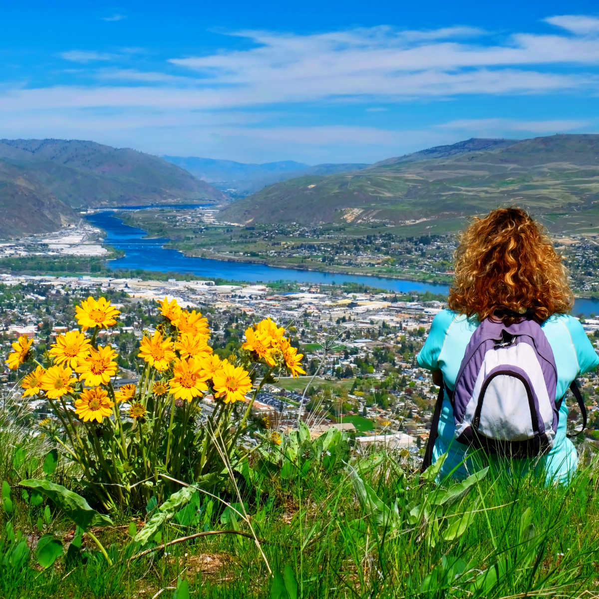 Woman with backpack sitting on the top of mountain in Wenatchee, Washington