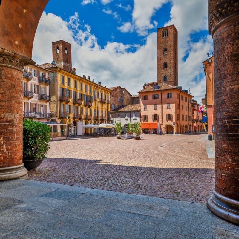 houses and medieval towers under beautiful sky in Alba, Piedmont, Northern Italy.