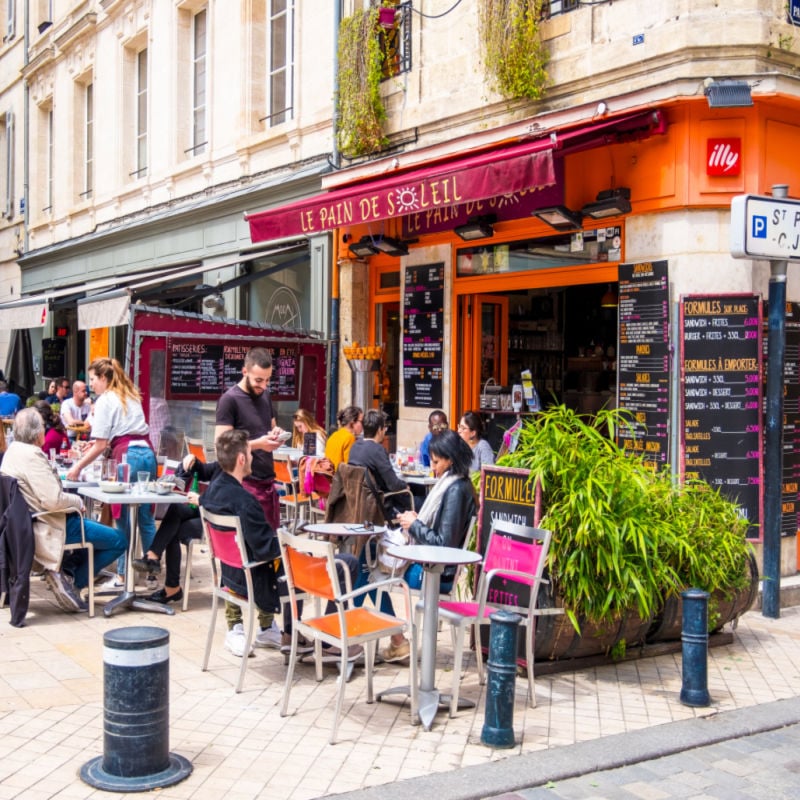 Residents of the city and tourists relax in the cafe on a street in Bordeaux, France