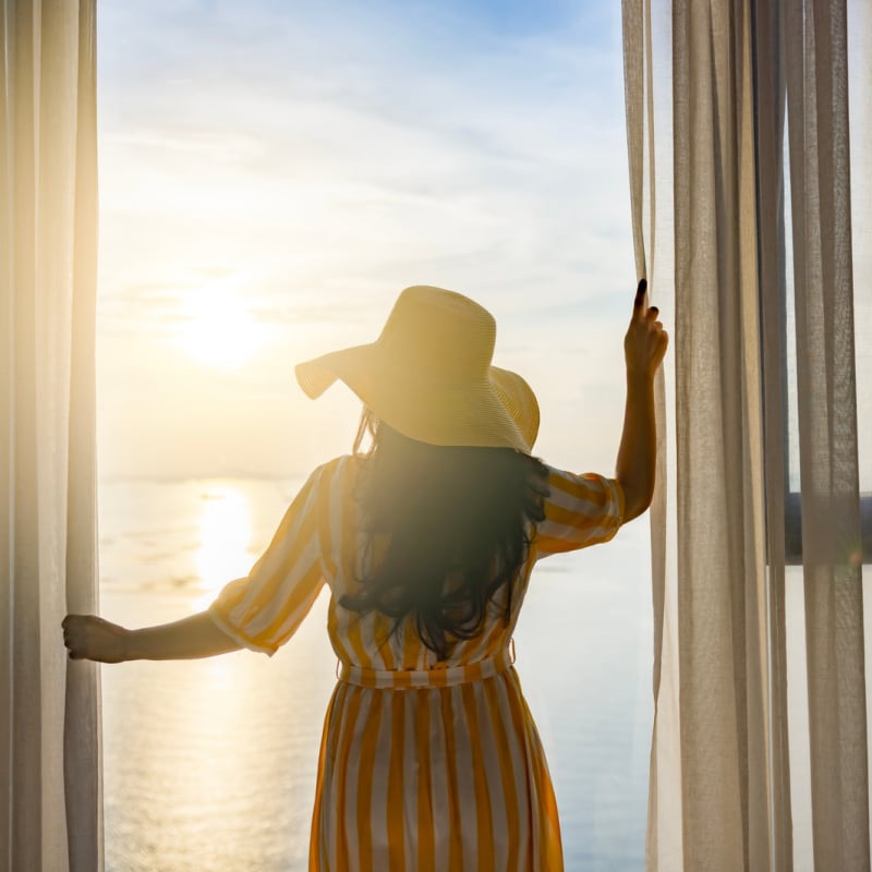 Vacationer viewing water from hotel room window