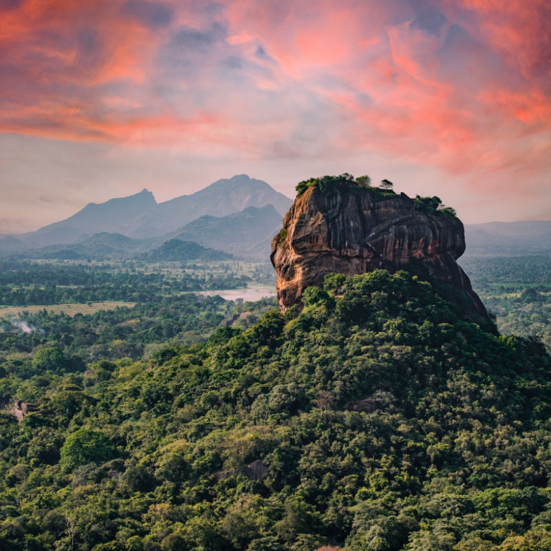 landscape shot of lion rock in sri lanka with forests around and mountains in the background