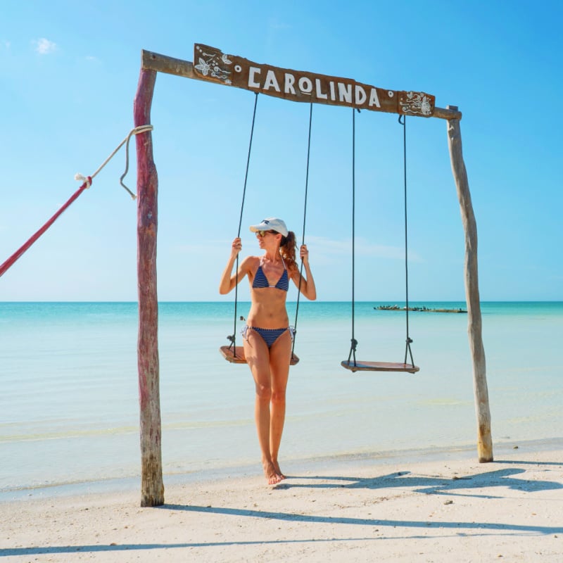 woman sitting on a wooden swing in front of the Caribbean Sea on Holbox Island