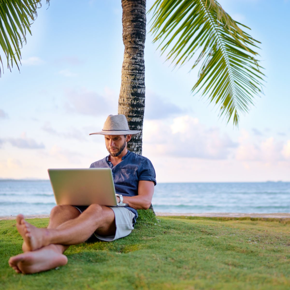 Digital nomad working under palm tree on Caribbean beach