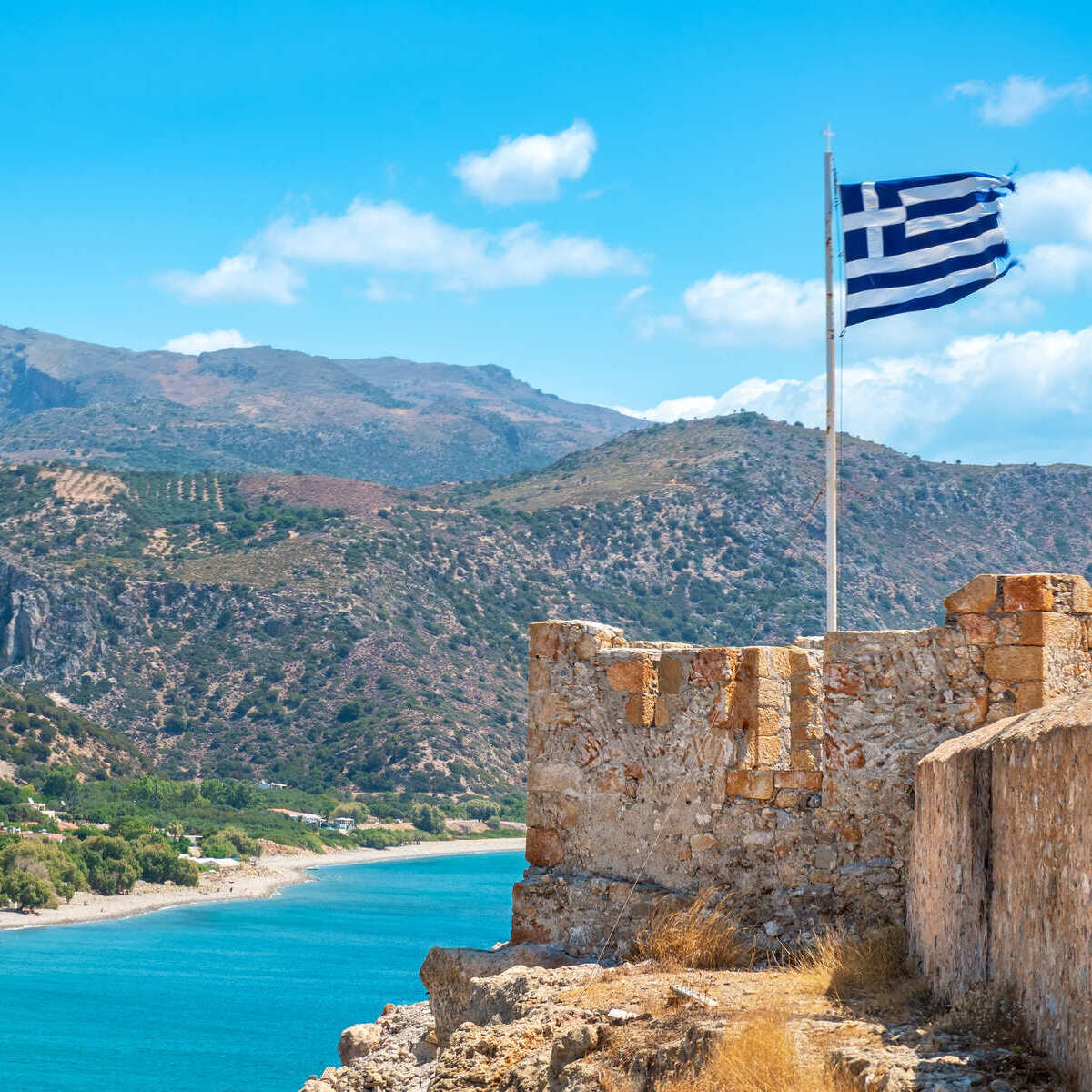 Greek Flag Flying Atop A Ruined Castle In Crete, Greece