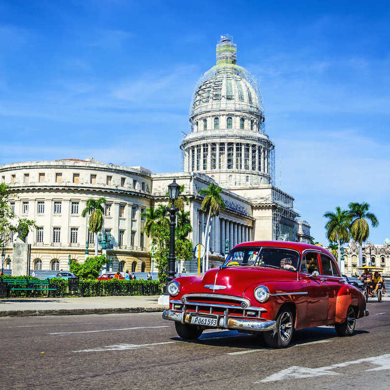 Vintage car driving past the Colonial Old Town of Havana, Cuba