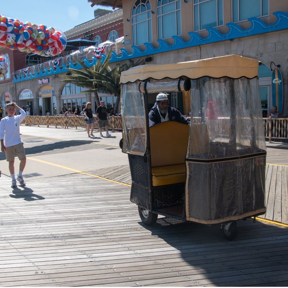 Man who pushing a famous rolling chair looking for a tourist to request a ride on the Atlantic City Boardwalk.