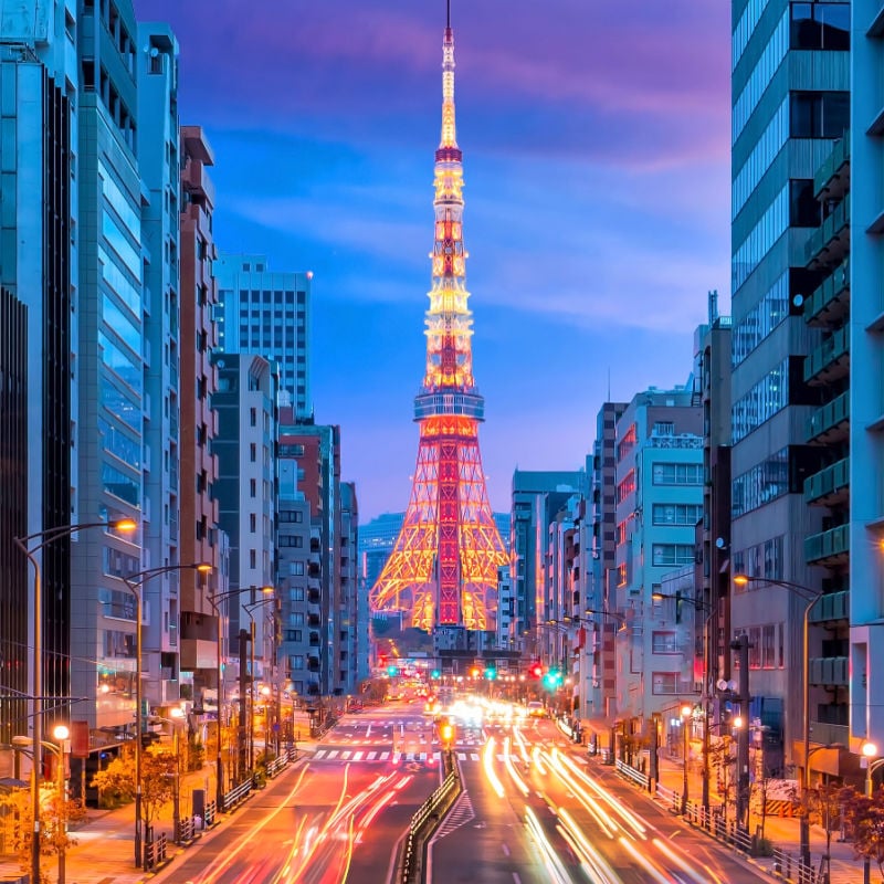 tokyo tower illuminated at night with busy streets in japan