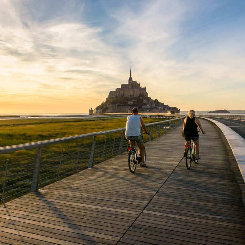 Tourists Cycling Towards Mont Saint Michel In France