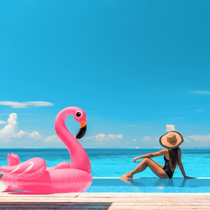 Young Woman Posing By The Poolside With A Floatable Pink Flamingo Facing The Caribbean Sea In Mexico