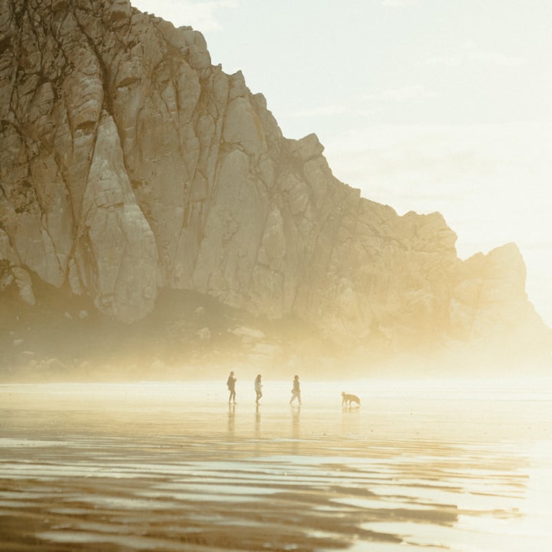 Family walking on beach near Morro Rock in Morro Bay, CA