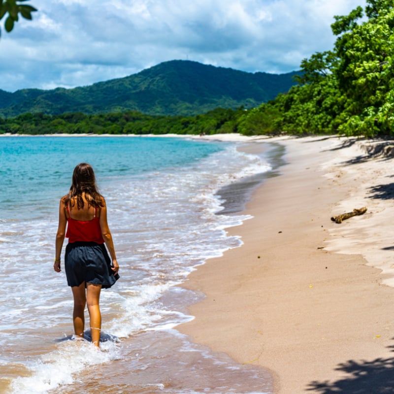 woman walks along a beach on the pacific coast in costa rica