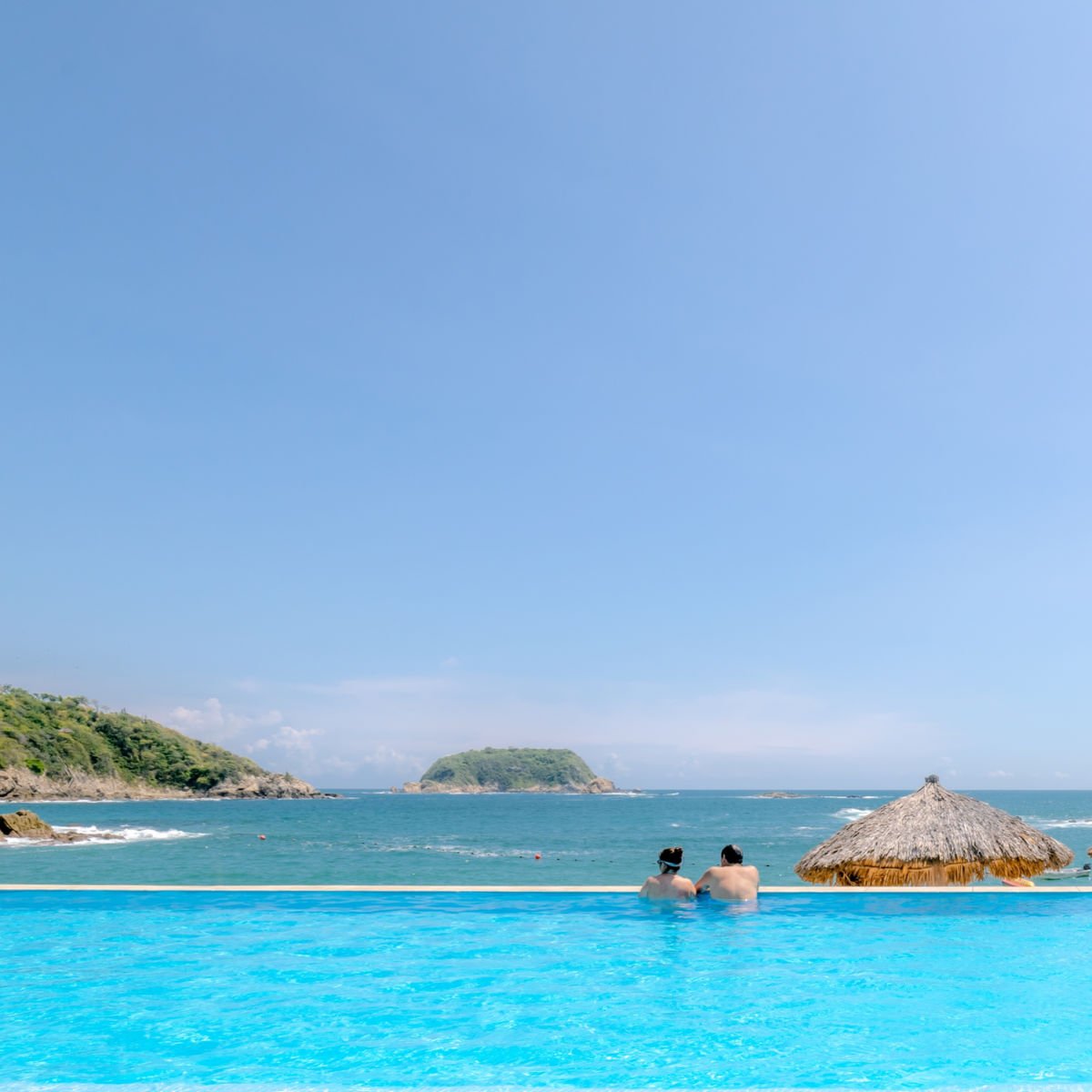 Couple in infinity pool overlooking Huatulco beach