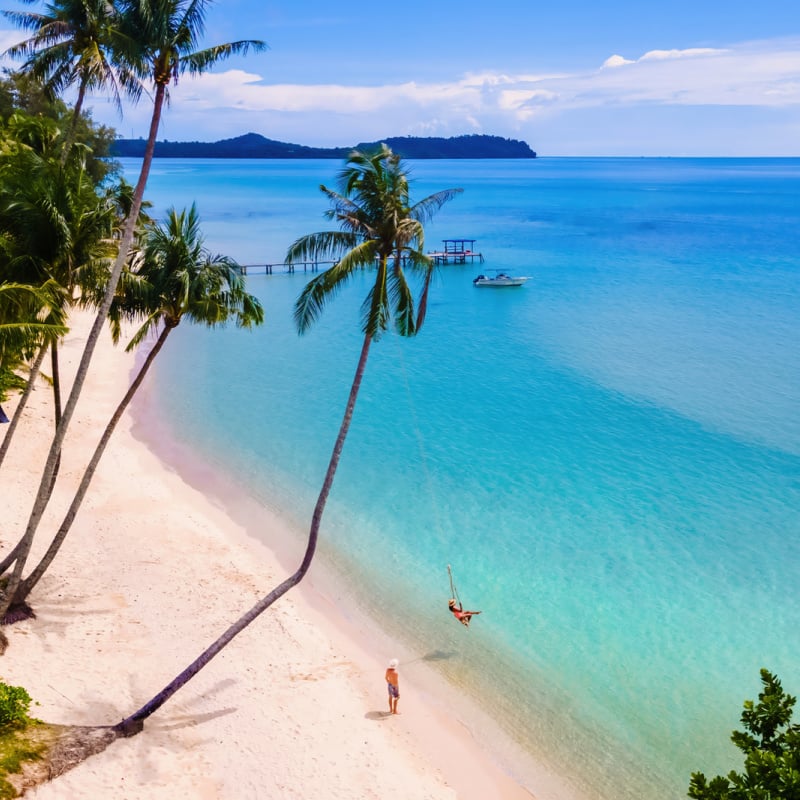 Tourist swinging on isolated beach in Koh Kood