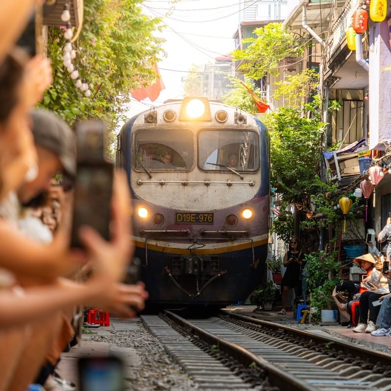 Tourists Taking Pictures As They Admire A Train Going Past A Narrow Street In Hanoi, Vietnam, Southeast Asia.jpg