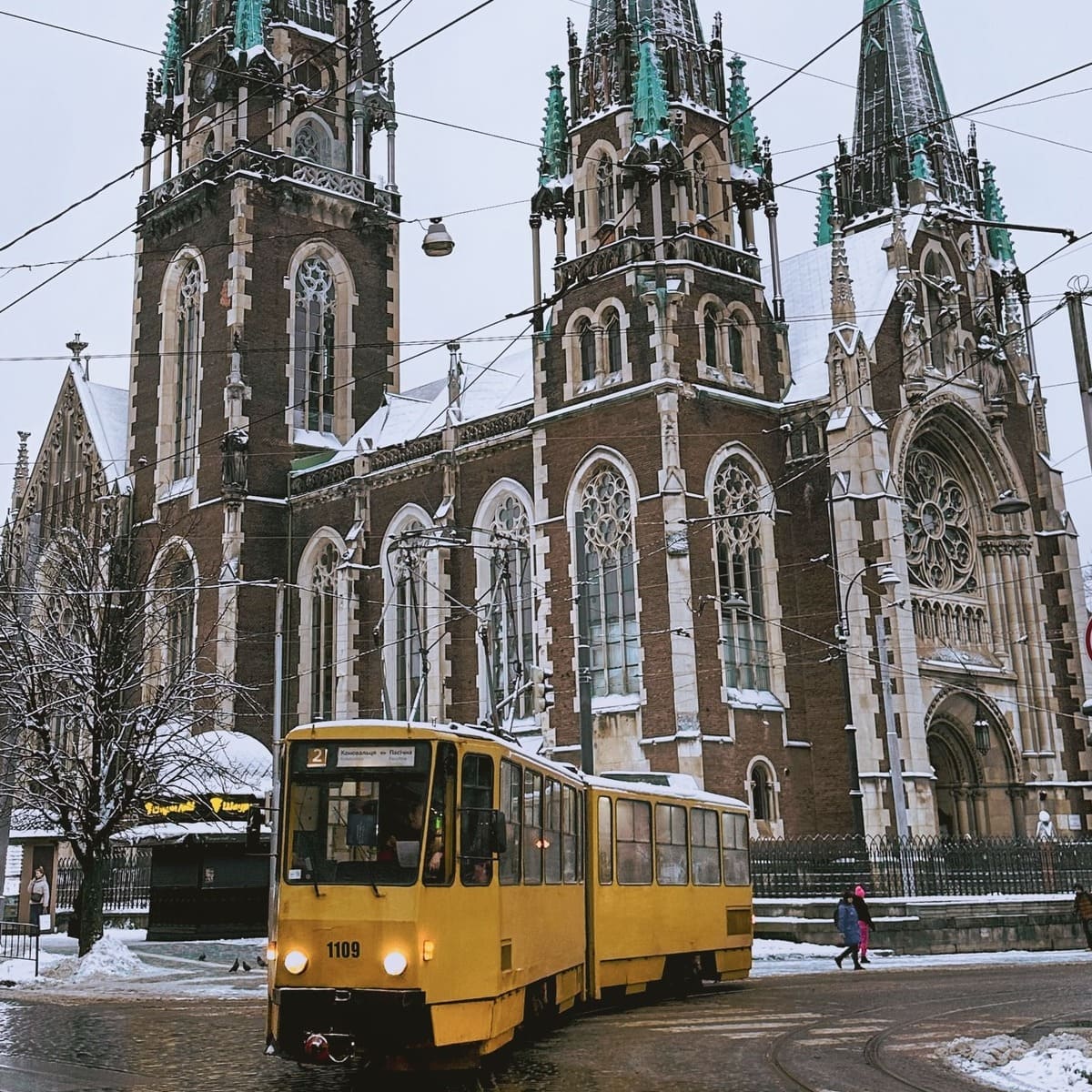 Yellow Tram Backed By A Gothic Church In Lviv, Ukraine