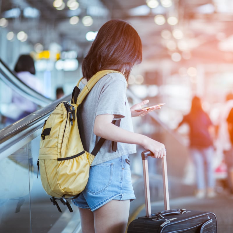 young female traveler on escalator at airport with baggage