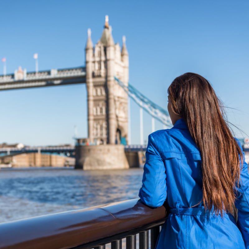 woman tourist solo female traveler in front of tower bridge in london, england