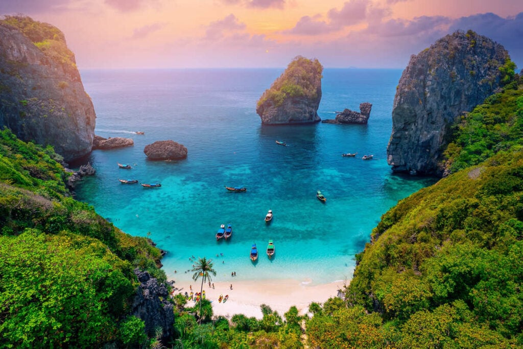 White sand beach in Thailand over looking rock formations and aqua blue sea